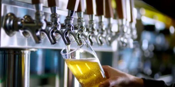 Tall glass with of beer being prepared to be served.